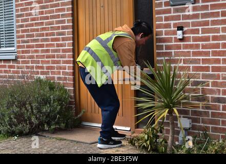 Basingstoke, Hampshire / UK - April 08 2020: Ein Amazon-Fahrer liefert während der Coronavirus-Sperrung ein Paket zum Haus eines Kunden. Stockfoto