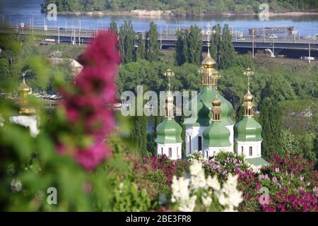 Malerischer Blick auf das Kloster Vydubychi und den Fluss Dnipro mit rosa und weißen Flieder, die im botanischen Garten in Kiew blühen Stockfoto