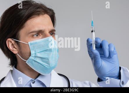 Coronavirus-Impfstoff. Männlicher Arzt in medizinischen Maske hält Spritze mit Injektion Stockfoto