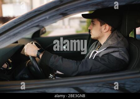 Mann sitzt im Auto. Schöner junger Mann, der ein Auto fährt Stockfoto
