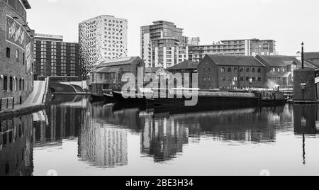 Moderne Gebäude und Hausbooten spiegeln sich im Wasser des Birmingham Canal alte Linie, die in die Innenstadt führt. Stockfoto