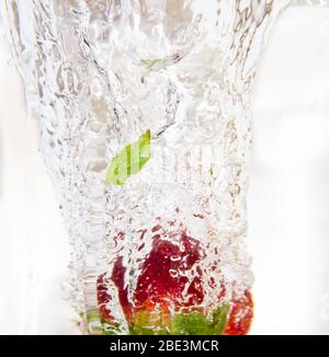 Eine Erdbeere fällt in ein frisches Glas Wasser und macht schöne Blasen, eine Art Frische Stockfoto