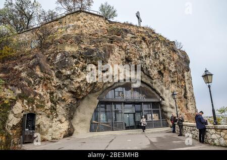 Budapest, Ungarn - 6. November 2019: Eingang zur Gellert Hill Cave Church, Sziklatemplom. Felsenkirche in der ungarischen Hauptstadt. Leute von den Touristen. Überqueren Sie die Spitze des Felsens. Stockfoto