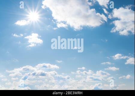 Sonne mit Sonnenstrahlen auf den blauen Himmel mit weißen Wolken. Tagsüber und bei schönem Wetter Stockfoto