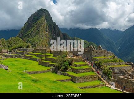 Hauptplatz von Machu Picchu Ruine mit landwirtschaftlichen Feldern und Touristen entlang des Wanderwegs, Provinz Cusco, Peru. Stockfoto