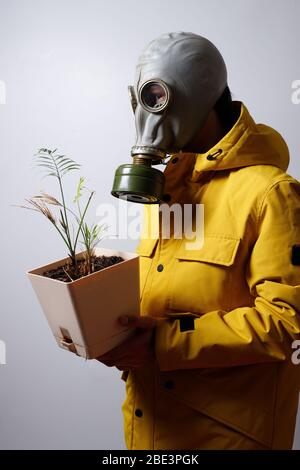 Ein Mann in einer Gasmaske mit einer Blume in der Hand, isoliert auf weißem Hintergrund. Covid-19 Virus Konfrontation Stockfoto
