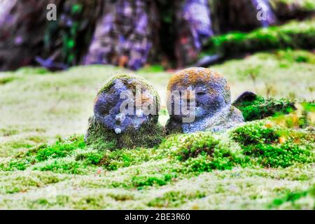 Immergrüne Moose und Gras im traditionellen japanischen Garten des Ohara-Dorfes in der Nähe von Kyoto mit ein paar Steinstatuen, die sich aneinander lehnen. Stockfoto