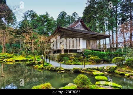 Ein stiller Teich mit Steintreppen gegenüber vom abgelegenen traditionellen japanischen Gebäude in einem japanischen Garten in der Nähe von Kyoto. Stockfoto