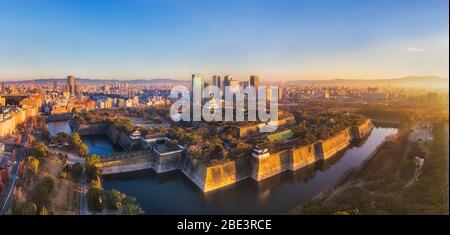 Luftaufnahme bei Sonnenaufgang in Osaka, der Stadt Japan, um den historischen Park mit altem Schloss und neuen modernen Wolkenkratzern. Stockfoto