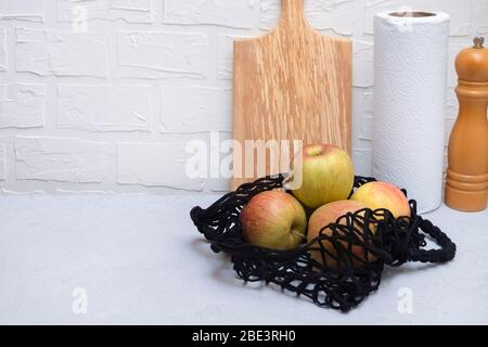 Netztasche mit Äpfeln auf neutralem Küchentisch mit Kopierfläche. Kunststoffabfälle reduzieren das Konzept Stockfoto