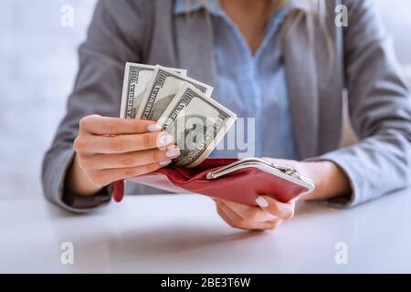 Verdienen Sie Geld in Quarantäne. Frau legt Dollar in Geldbörse Stockfoto