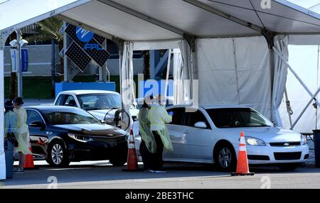 Daytona, USA. April 2020. Mitarbeiter im Gesundheitswesen von AdventHealth bieten am 11. April 2020 auf dem Daytona International Speedway in Daytona Beach, Florida, Drive-Thru-COVID-19-Tests an. Die Ergebnisse des Speicheltests werden in 2-3 Tagen vorliegen. Kredit: Paul Hennessy/Alamy Live News Stockfoto