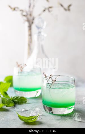 Kaltes Sommergetränk mit Basilikumblättern in Gläsern. Mojito, Eistee, Limonade mit Basilikum. Stockfoto