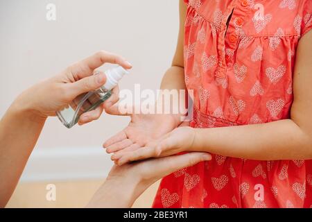 Mama verwendet antiseptisches Spray auf der Handfläche der Tochter Stockfoto