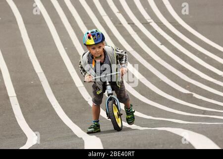 Ein kleiner Junge schiebt sein Fahrrad im modernen Superkilen-Park im dänischen Nørrebro-Viertel Kopenhagen den Hügel hinauf. Stockfoto