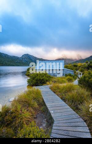 Ikonische Aussicht auf der Promenade, die zum hölzernen Bootshaus am Dove Lake führt, im Cradle Mountain National Park in Tasmanien, Australien. Stockfoto