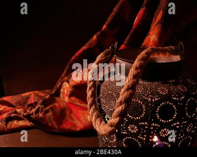 Arabische Laterne in der Nähe eines roten orientalischen Stoffes auf einem braunen Holzhintergrund.Eid Lampe oder Laterne für Ramadan und andere islamische muslimische Feiertage, mit Kopie Stockfoto