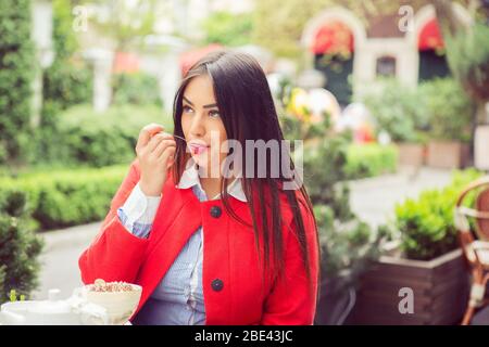 Nahaufnahme Porträt einer jungen Frau, die Eis leckt Löffel im Freien im Sommer Terrasse Café. Seitenansicht Stockfoto