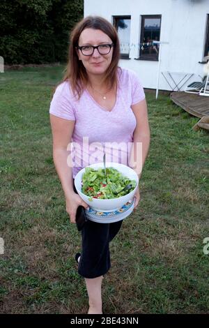Polnische Frau hält Schüssel mit frischen grünen Salat für einen Familie Grill im Freien in ihrem Hof. Zawady Gmina Rzeczyca Polen