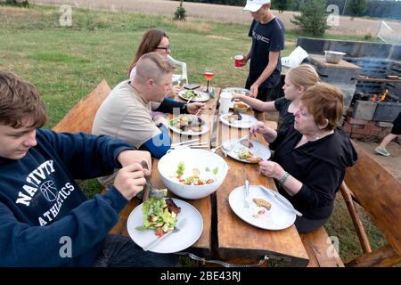 Polnische Familie von drei Generationen genießen ein Essen am Picknicktisch in ihrem Hof. Zawady Gmina Rzeczyca Polen Stockfoto