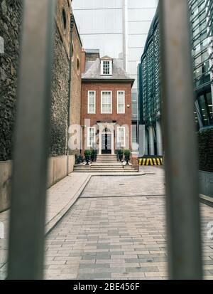 Blick durch das Tor des schmalen britischen Red Brick House in einem dichten modernen Stadtbild, London, Großbritannien Stockfoto