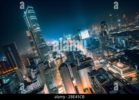 Panoramablick auf die Dächer futuristischer Wolkenkratzer bei Nacht in lebendigen Farben, Hongkong