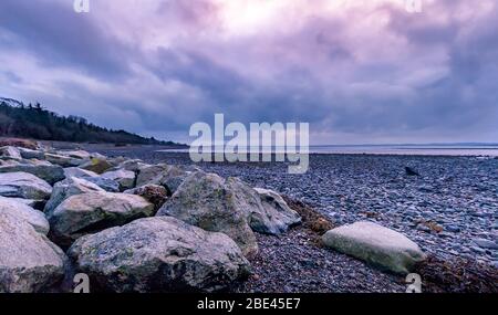 Ruhige und ruhige irische Küste und Meer unter buntem Sonnenuntergang mit Magenta Sky, County Down, Nordirland Stockfoto