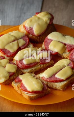 Frisches Sandwich mit Käse und Wurst. Warme Sandwiches. Sandwich mit Wurst und Hartkäse auf einem Schneidebrett. Stockfoto