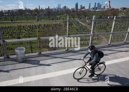 New York, USA. April 2020. Ein Mann fährt mit dem Fahrrad am Calvary Cemetery vorbei, der wegen der Coronavirus-Pandemie für Besucher gesperrt ist, in Queens of New York, USA, am 11. April 2020. Die Gesamtzahl der Todesfälle aufgrund von COVID-19 in den Vereinigten Staaten übertroffen 20,000 Samstag Nachmittag, nach Daten vom Center for Systems Science and Engineering (CSSE) an der Johns Hopkins University zusammengestellt. Kredit: Michael Nagle/Xinhua/Alamy Live News Stockfoto