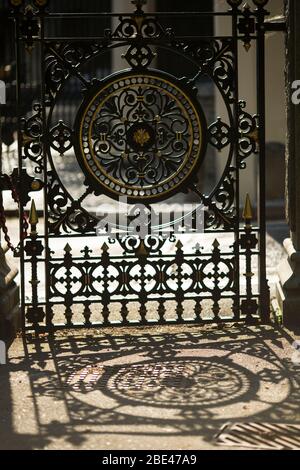 Ein schmiedeeisernes viktorianisches Tor wirft einen verzierten Schatten am Eingang zum Highgate Cemetery in Swain's Lane in London, England, Großbritannien. Stockfoto