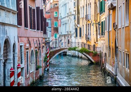 Paare umarmt auf gewölbter Fußgängerbrücke über den Kanal, bunte Gebäude auf beiden Seiten; Venedig, Italien Stockfoto