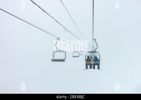 Skifahrer fahren mit dem Sessellift durch die Wolken, Sun Peaks Resort; Sun Peaks, British Columbia, Kanada Stockfoto