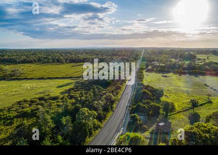 Luftaufnahme der Straße, die durch landwirtschaftliche Flächen in hellem Sonnenlicht in Australien führt Stockfoto
