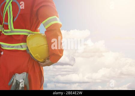 Ingenieur hält harten Helm mit Wolke und blauen Himmel Hintergrund, Sicherheit erstes Konzept Stockfoto