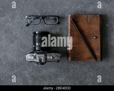 Brillen, braunes Leder Notizblock und Kamera auf grauem Betongrund Stockfoto