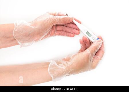 Weibliche Hände tragen in Vinyl-Handschuhe halten ein digitales Thermometer. Nahaufnahme, isoliert auf weißem Hintergrund Stockfoto