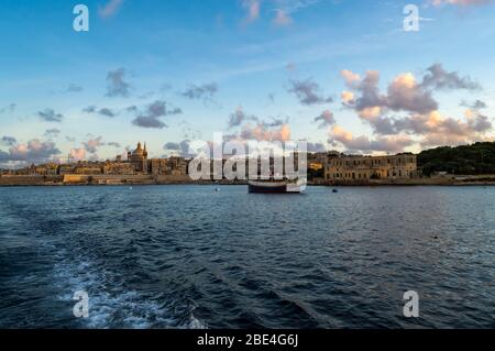 Blick auf Valletta Skyline am schönen Sonnenuntergang von Sliema mit Kirchen Unserer Lieben Frau auf dem Berg Karmel und St. Paul's Anglican Pro-Cathedral, Va Stockfoto