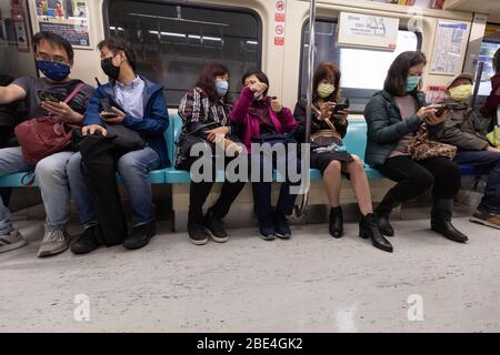 Pendler in der Taipei U-Bahn tragen chirurgische Masken als Schutz gegen das Covid-19 Coronavirus. Stockfoto