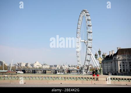 London, Großbritannien. April 2020. Tag der Lockdown in London. Ein Paar auf der Westminster Bridge, mit dem London Eye hinter sich, in London am Ostersamstag. Es ist der erste Feiertag des Jahres, und viele Menschen genießen das lange Wochenende, indem sie ausgehen und unterwegs oder in den Urlaub, aber dieses Jahr ist das Land auf Sperre wegen der COVID-19 Coronavirus Pandemie. Menschen dürfen nicht zu Hause verlassen, außer für minimale Lebensmittel einkaufen, medizinische Behandlung, Bewegung - einmal pro Tag und wesentliche Arbeit. COVID-19 Coronavirus Lockdown, London, Großbritannien, am 11. April 2020 Quelle: Paul Marriott/Alamy Live News Stockfoto