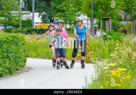 Junge Familie eine Tour auf Inlineskates im städtischen Park an einem sonnigen Mittag im Sommer Stockfoto