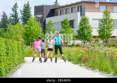 Junge Familie eine Tour auf Inlineskates im städtischen Park an einem sonnigen Mittag im Sommer Stockfoto