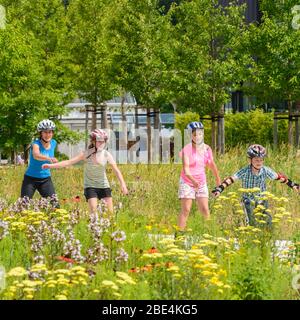 Junge Familie eine Tour auf Inlineskates im städtischen Park an einem sonnigen Mittag im Sommer Stockfoto