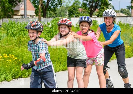 Junge Familie eine Tour auf Inlineskates im städtischen Park an einem sonnigen Mittag im Sommer Stockfoto