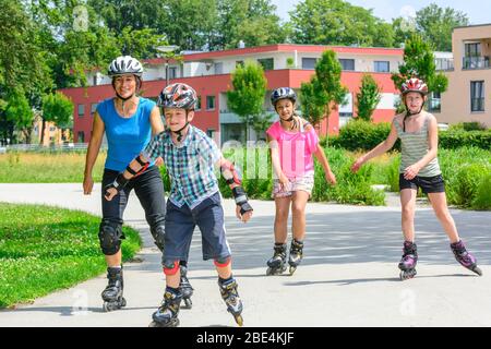 Junge Familie eine Tour auf Inlineskates im städtischen Park an einem sonnigen Mittag im Sommer Stockfoto