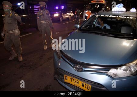 Jakarta, Indonesien. April 2020. Beamte inspizieren einen Taxifahrer während der Umsetzung der umfassenden sozialen Einschränkung im Rahmen der COVID-19-Pandemie in Jakarta, Indonesien am 11. April 2020. Der indonesische Präsident Joko Widodo hat den Ausbruch als Notstand für die öffentliche Gesundheit erklärt und eine staatliche Verordnung über umfangreiche soziale Beschränkungen erlassen. Kredit: Aditya Irawan/Xinhua/Alamy Live News Stockfoto