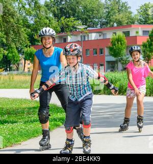 Junge Familie eine Tour auf Inlineskates im städtischen Park an einem sonnigen Mittag im Sommer Stockfoto