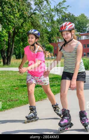 Junge Familie eine Tour auf Inlineskates im städtischen Park an einem sonnigen Mittag im Sommer Stockfoto