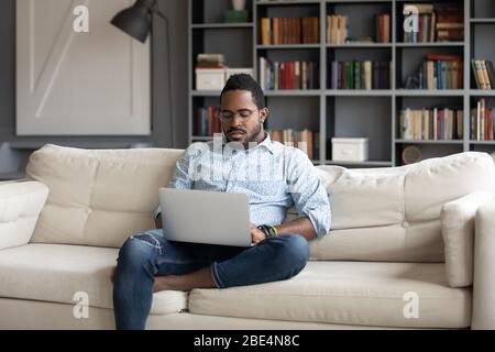 Fokussierter junger afroamerikanischer Geschäftsmann, der remote online arbeitet. Stockfoto
