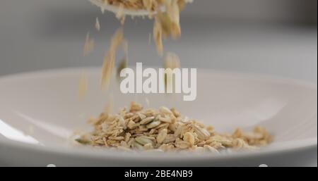 Müsli mit Mandelflocken und Kürbiskernen fallen in Weiß Nahaufnahme der Schüssel Stockfoto