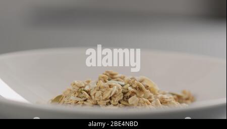 Müsli mit Mandelflocken und Kürbiskernen in weißer Schale Nahaufnahme Stockfoto